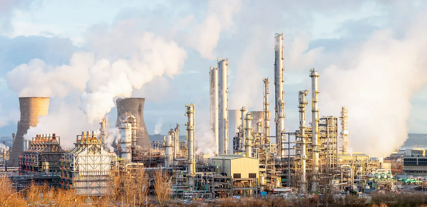 Industrial refinery facility with natural-draft cooling towers emitting steam